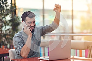 Excited happy bearded freelancer reading email with results about victory in modern online contest sitting at laptop photo