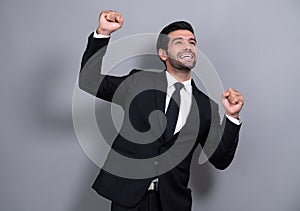 Excited and happy businessman dressed in black formal suit. Fervent