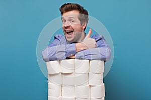 Excited happy caucasian man holding a pile of toilet paper showing thumb up