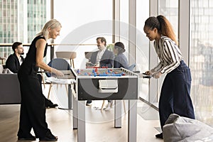 Excited happy diverse colleagues women playing table soccer