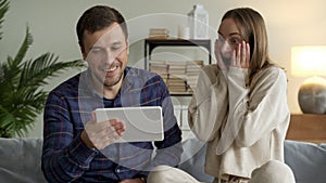 Excited happy family couple looking at digital tablet feel winners overjoyed by lottery winning bet bid, celebrate good