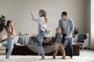 Excited happy family dancing to music in living room