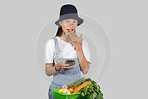 Excited and Happy Farmer Girl with Fruits and vegetables on a mobile phone