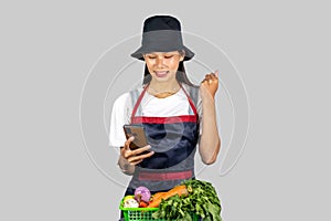 Excited and Happy Farmer Girl with Fruits and vegetables on a mobile phone