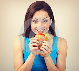 Excited happy hungry woman wanting to bite tasty burger on blue background. Closeup