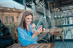 Excited happy Indian girl celebrating online win, holding phone, looking at camera sitting at home balcony