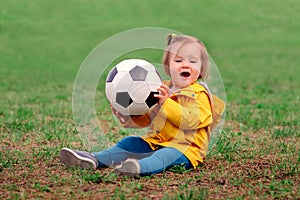 Excited happy little girl holding football ball and shouting of happiness