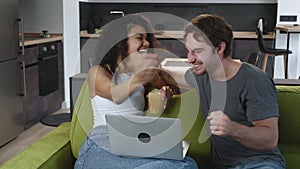 Excited happy multiracial couple looking at screen of laptop feel winners surprised by lottery betting winning bid