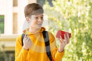 Excited happy teenager boy winner feeling joy smiling and looking at smartphone. Boy using phone, winning lottery game