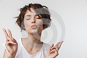 Excited happy woman posing isolated over white wall background showing peace gesture