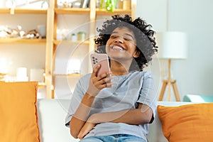 Excited happy young black african american woman holding cell phone laughing feeling joy getting mobile message