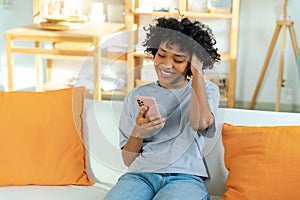 Excited happy young black african american woman holding cell phone laughing feeling joy getting mobile message