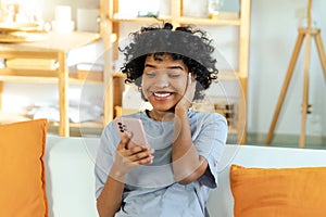 Excited happy young black african american woman holding cell phone laughing feeling joy getting mobile message