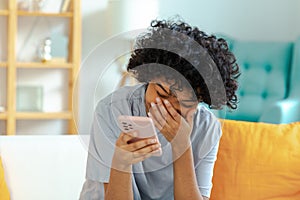 Excited happy young black african american woman holding cell phone laughing feeling joy getting mobile message