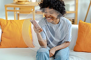 Excited happy young black african american woman holding cell phone laughing feeling joy getting mobile message