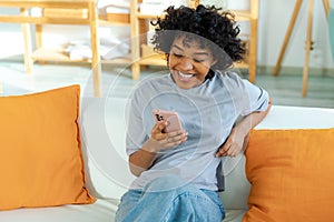 Excited happy young black african american woman holding cell phone laughing feeling joy getting mobile message
