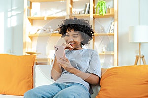 Excited happy young black african american woman holding cell phone laughing feeling joy getting mobile message