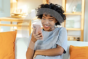 Excited happy young black african american woman holding cell phone laughing feeling joy getting mobile message
