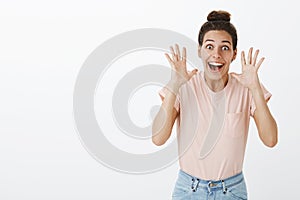 Excited and happy young female friend retelling awesome news cannot hide amazement raising hands near head smiling photo