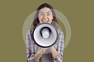 Excited happy young woman announcing by megaphone on isolated background