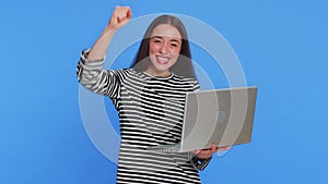 Excited happy young woman working on laptop winning online lottery game celebrating success victory