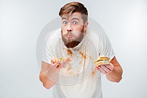 Excited hungry bearded man greedily eating hamburgers