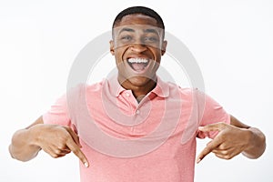 Excited and impressed happy african american man standing high pointing down with amazed and cheerful expression