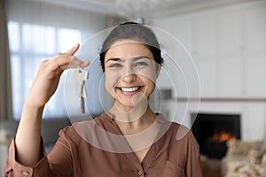 Excited indian female become homeowner look at camera hold key