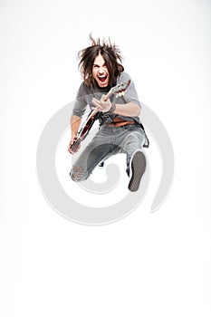 Excited joyful male guitarist with electric guitar shouting and jumping