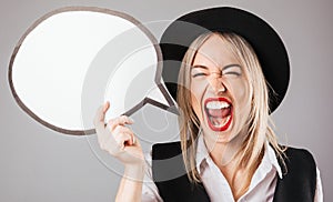 Excited joyful screaming woman in black hat and red lips holding emoty white spech buble