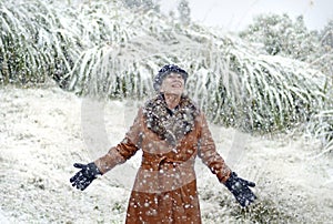 Excited joyful woman standing in falling snow for first time in life