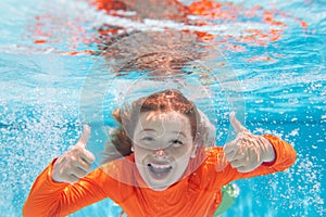 Excited kid boy with thumbs up swim and dive underwater, kid with fun in pool under water. Active healthy lifestyle