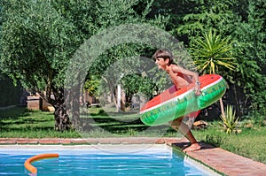 Excited kid with inflatable ring at pool& x27;s edge ready to jump