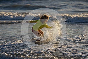 Excited kid playing in splashing water on summer sea. Summer vacation. Kid play of waves at sea. little kid playing in