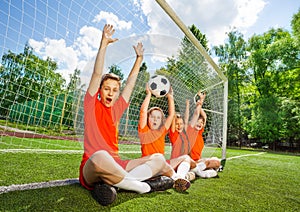 Excited kids sit in row with football and arms up