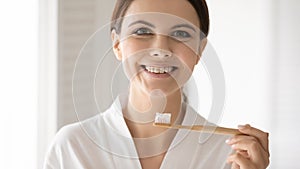 Excited lady with healthy teeth holding bamboo brush with paste