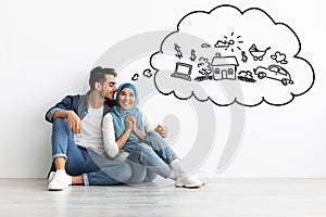 Excited lady in hijab sitting on floor with her husband