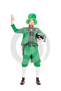 Excited leprechaun gesturing and holding pot of gold,