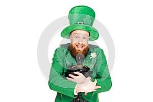 Excited leprechaun in green hat holding pot of gold