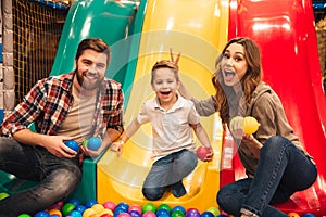 Excited little boy playing on a slide with his parents