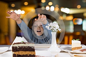 Excited little boy reaching for a slice of cake