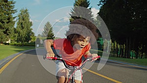 Excited little boy riding bicycle in public park