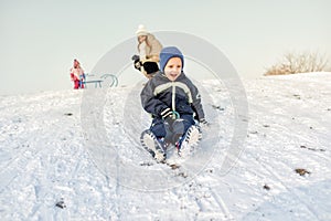 Excited little boy on snow tobogganing