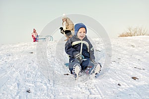 Excited little boy on snow tobogganing