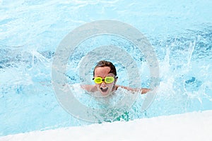 Excited little boy splashing in pool and screaming