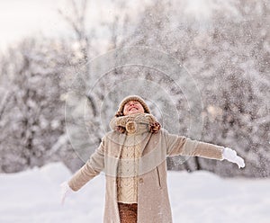 Excited little girl enjoying snow falling on face, playing in snowy forest during first snowfall
