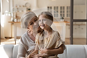 Excited little girl grandchild sit on loving mature grandmother knees