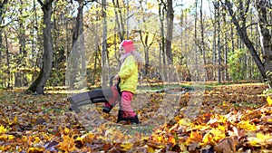 Excited little girl holding leaf blower tool in autumn garden. Child blow leaves