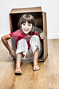 Excited little girl sitting in cardboard box playing for surprise