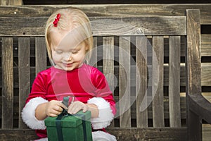 Excited Little Girl Unwrapping Her Gift on a Bench